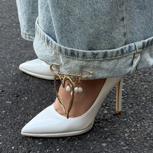 Detail of a golden heart brooch and faux pearls pinned on light blue denim jeans