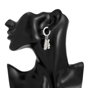 Détail de créoles argentées avec pendentifs texture roche et chaîne perlée