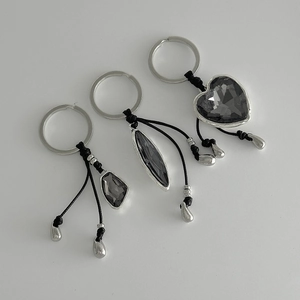 Three-piece set of silver keychains with dark grey acrylic crystals and black woven ropes