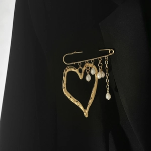 Lava-textured gold heart brooch with elegant pearl tassels on black suit lapel