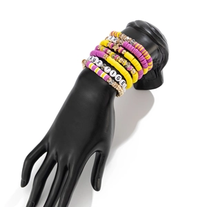 Detail of colorful polymer clay disc beads and gold spacers on layered stretch bracelets