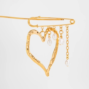 Detail of golden heart brooch featuring irregular pearl tassels and pin mechanism