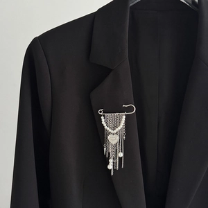 Détail de la broche épingle argentée avec glands en perles et pendentif cœur sur revers noir