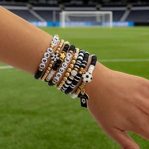 Detail of multi-layer soccer bracelets with Game Day beads on a football field background