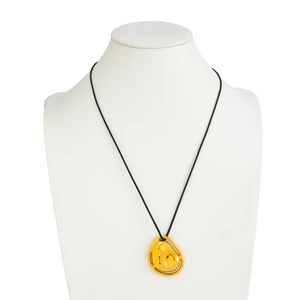 Detalle de un colgante de gota dorado irregular minimalista en un cordón negro fino