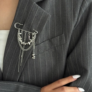 Détails de broche à chaînes argentées multicouches et pendentif sur veste grise