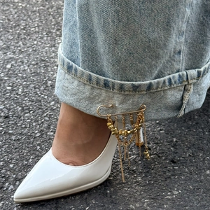 Détail d'une broche à franges dorée avec perles fixée sur un jean comme accessoire de mode