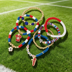 Detail of soccer themed bracelets with red, white, blue beads and USA charms on grass