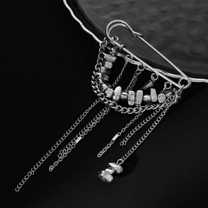 Détails d'une broche punk argentée avec chaînes à franges et perles métalliques irrégulières