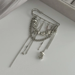 Détail d'une broche à pampilles argentée avec chaînes cubaines et perles sur soie
