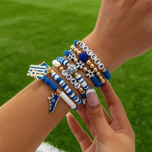 Detail of soccer themed beaded bracelets on grass with clay beads and sports charms