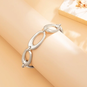 Detailansicht eines silbernen Gliederkettenarmbandes vor warmem orangefarbenem Hintergrund