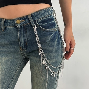 Close-up of layered silver metal pant chain with star charms and faux pearls on denim
