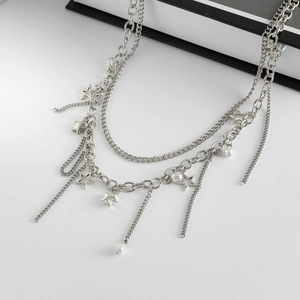 Detail of layered silver star and faux pearl trouser chain with sleek metallic tassels