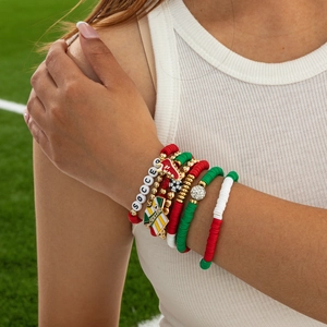 Detail of multi-layered bohemian soccer bracelets with beads on a grass background