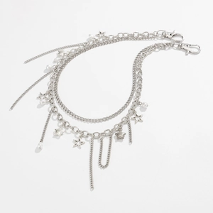 Detail van een meerlaagse zilveren broekketting met metalen sterren en witte parels