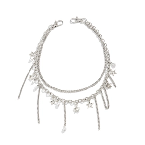 Detailopname van de meerlaagse zilveren sterbedels en parels aan de denim tailleketting