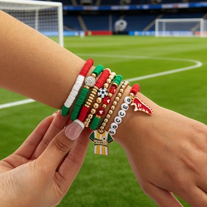 Close-up of a stacked soccer themed beaded bracelet set featuring athletic charms on a wrist