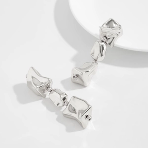 Gros plan de boucles d'oreilles argentées irrégulières avec une finition miroir polie