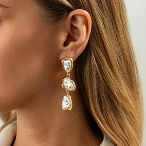 Boucles d'oreilles pendantes vintage dorées avec perles baroques portées par un mannequin