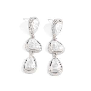 Détail macro de boucles d'oreilles pendantes à trois perles baroques et bordures argentées