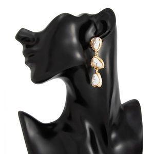 Détail de boucles d'oreilles pendantes en perles baroques sur un buste de mannequin