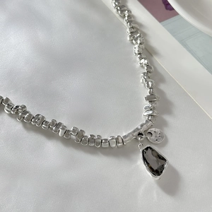 Close-up of silver irregular beads and black crystal pendant on a layered metal necklace