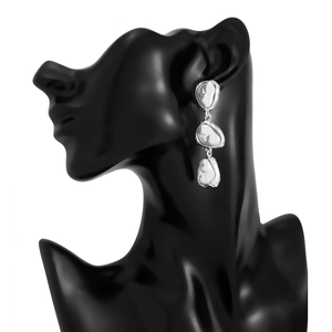 Détail de boucles d'oreilles pendantes en perles argentées sur un buste de mannequin