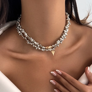 Detail of layered silver beaded necklace featuring a gold heart charm and metallic beads