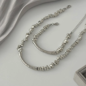 Minimalist silver beaded jewelry set featuring irregular beads and curved metal bar