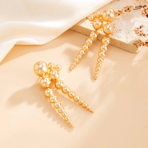 Détail de boucles d'oreilles dorées en perles CCB avec pompon sur soie et pierre élégante