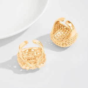 Detail of two gold-plated rings with textured dots and geometric hollow grid patterns