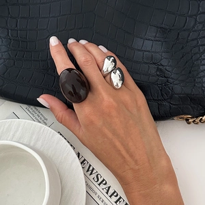 Detail of vintage acrylic amber ring and silver irregular metal ring on hand