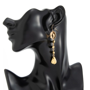 Boucles d'oreilles dorées à pampilles martelées présentées sur un buste de mannequin