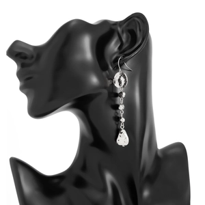 Détail de longues boucles d'oreilles à pompons argentés avec plaques en métal martelé