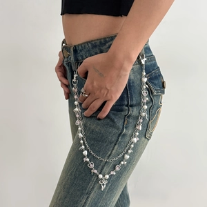 Detail of silver pant chain with pearls and pink beads on denim jeans belt loop