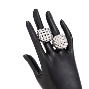 Detailed view of woven silver metal ring and domed pavé sphere ring on a hand model