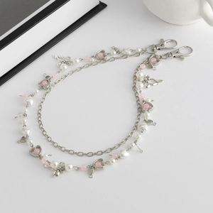 Detail van roze harten en metalen strikken op zilveren heupketting met parels en sluiting