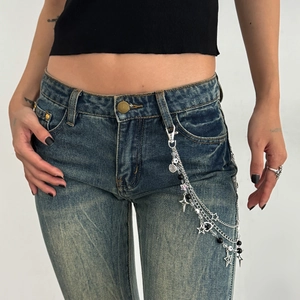 Detail of punk layered metal waist chain with stars and pearls on denim pants