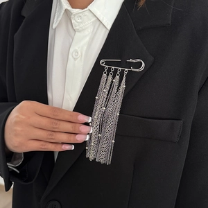 Detailansicht der silbernen Stern-Quasten-Brosche mit Ketten auf schwarzem Blazer