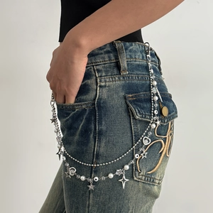 Y2K tailleketting detail met zilveren sterren, parels en hartjes aan een spijkerbroek