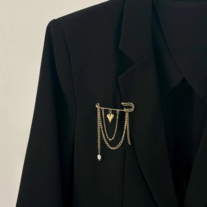 Golden tassel safety pin brooch with heart pendant and pearl on black suit lapel