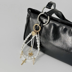 Chic leopard bow pearl bag charm with golden metal crosses and heart pendants on black bag