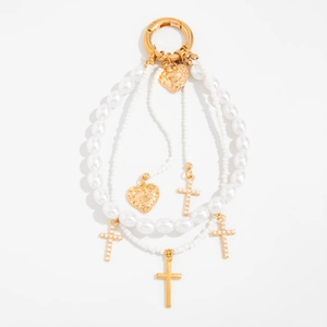 Detalle de cadena de perlas multicapa con colgantes de corazón dorado y cruz para bolso