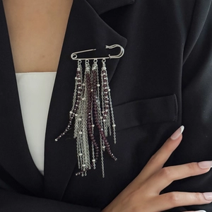 Hip hop style silver safety pin brooch with purple bead tassels on a black suit lapel