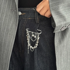 Macro shot of a silver star and heart multi-chain brooch on black denim jeans