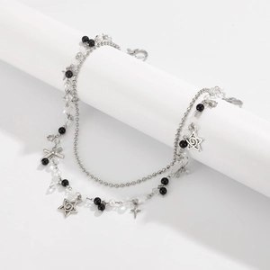 Detail of silver double-layer punk chain with beads, stars, and cross pendants on stand
