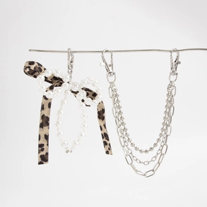 Detail of faux pearl bow keychain with leopard ribbon and layered metal chains