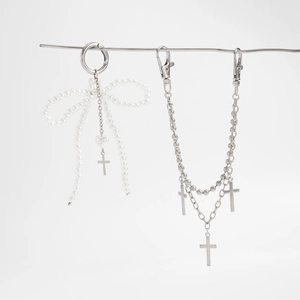 Detail of multilayer silver chain bag charm with pearl bow and metallic cross pendants