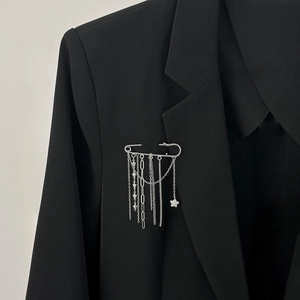 Detail of silver safety pin brooch with hanging star chain tassels on black blazer